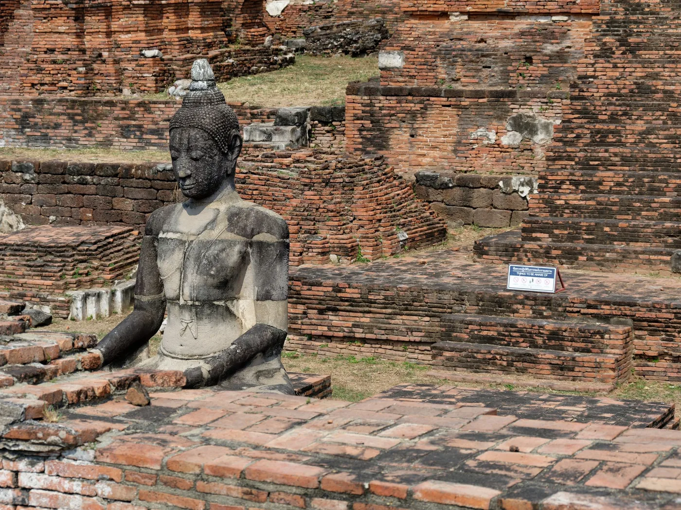 Una statua di Buddha seduto tra le rovine di Ayutthaya